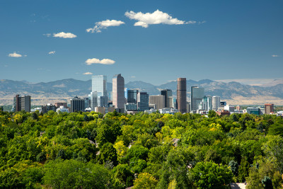 The towering high rises of Denver's downtown sit between the Front Range of the Rocky Mountains to the west and the tree lined neighborhoods and parks of the city to the east.